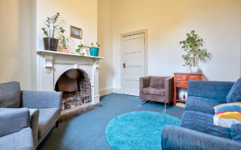 Image of the counselling room: two armchairs, a couch and plants in a light room