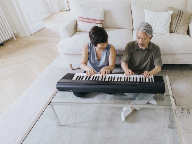 Older couple sitting on the floor and playing the keyboard together
