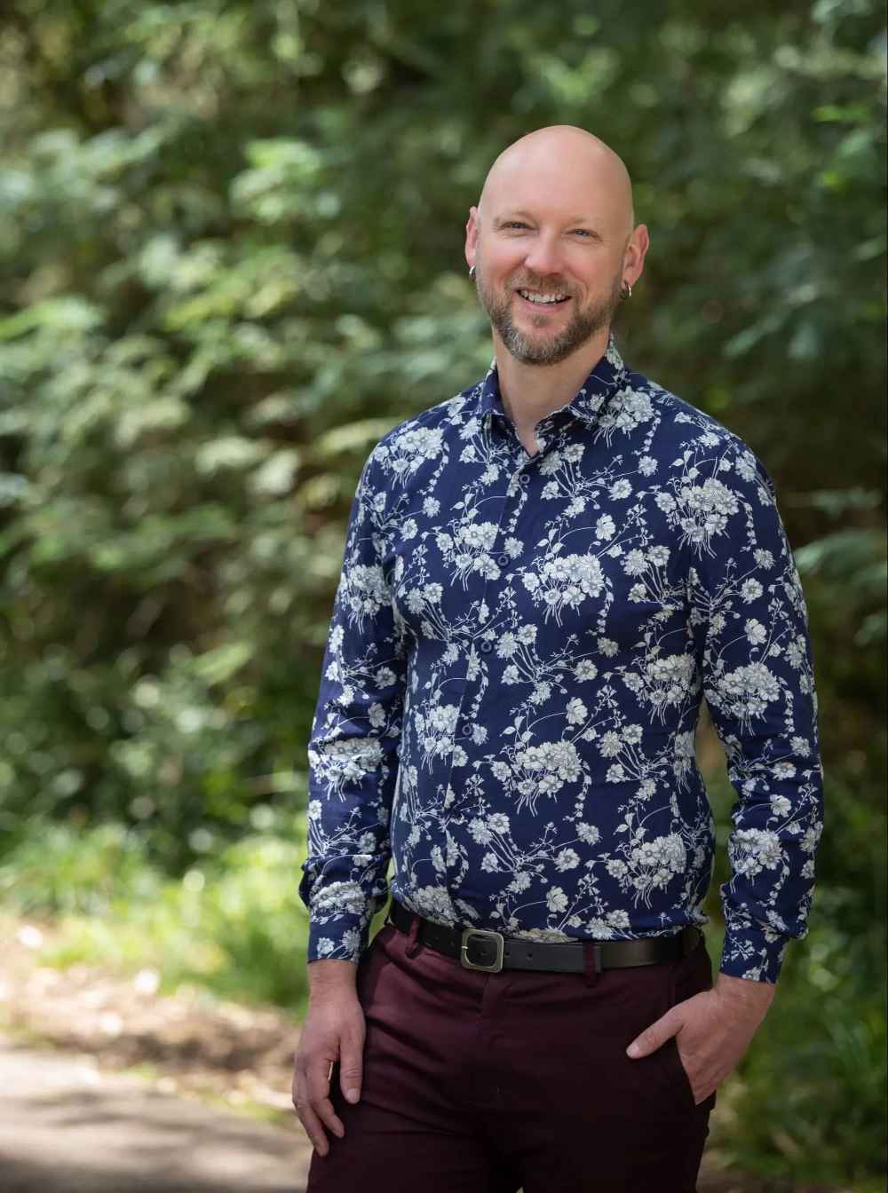 A picture of Robin Wilkinson standing against dappled trees and smiling