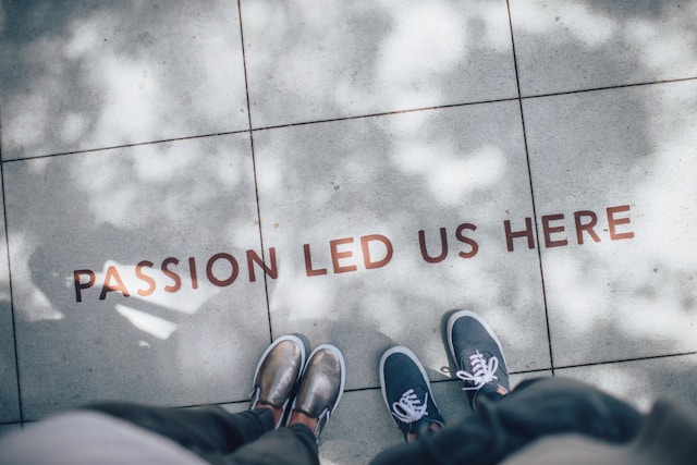 Two pairs of feet on the ground with the words "Passion led us here" stencilled on them