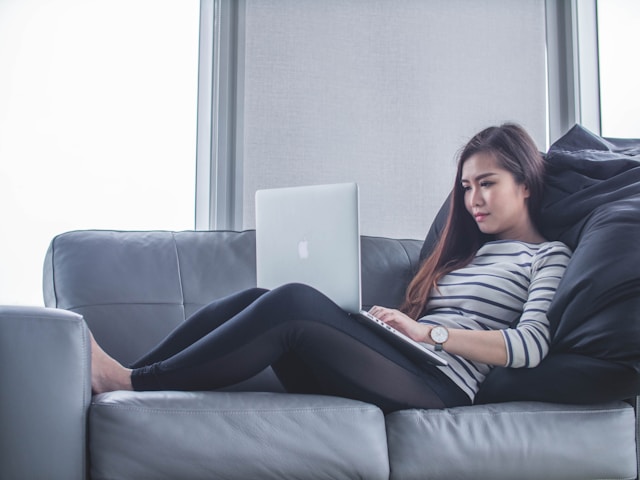 Woman sitting on a couch facing laptop