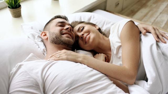 Happy couple snuggling in bed